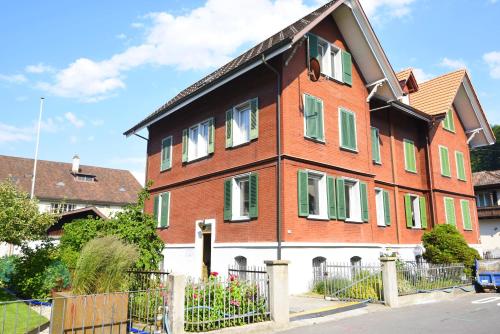 a large red brick building with green shuttered windows at New West Station in Interlaken