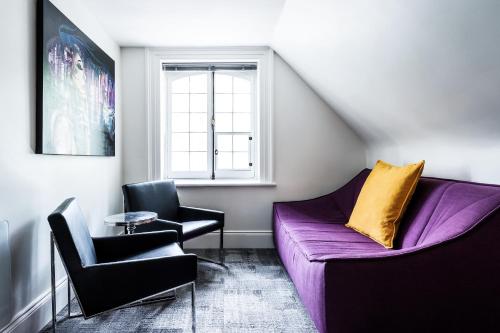 a living room with a purple couch and two chairs at C3- Hotel Art De Vivre in Quebec City
