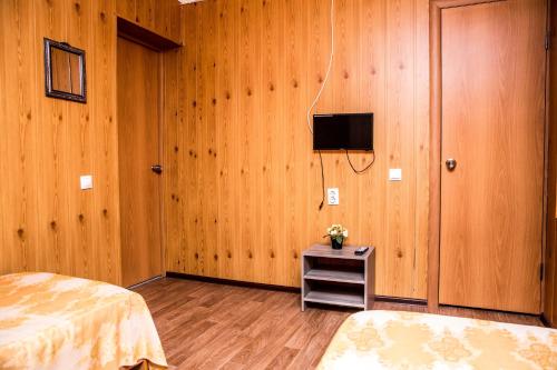 アルヒーポ・オシポフカにあるGuest House Vishnevaya 28aのウッドパネルのベッドルーム(テレビ、ベッド付)