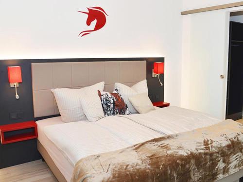 a bedroom with a large white bed with red lamps at Hotel Rotes Einhorn **** in Düren - Eifel