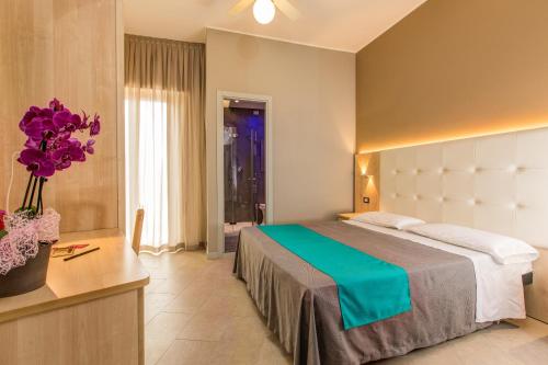 ガビッチェ・マーレにあるHotel Romanticoのベッド、テーブル、花が備わるホテルルームです。