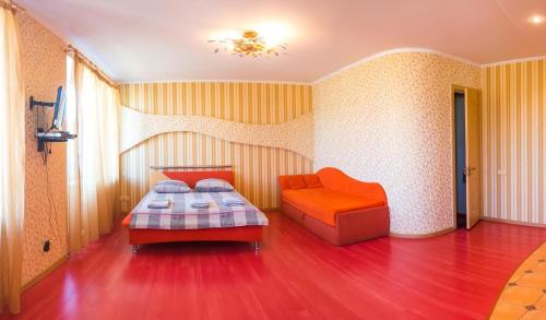ヘルソンにあるLuxury studio in the Very centerのベッドルーム(オレンジ色のベッド1台、ソファ付)