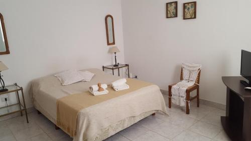 1 dormitorio con 1 cama con toallas y silla en Antigua Fonda Hosteria en Concepción del Uruguay