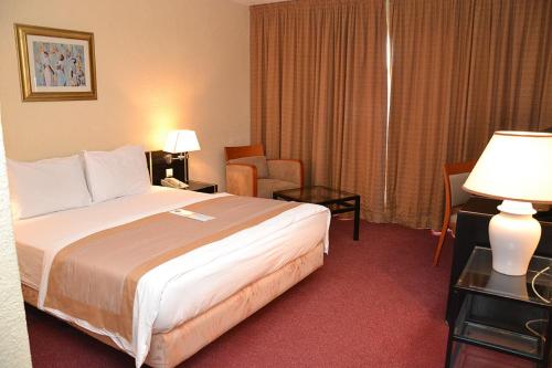 a hotel room with a bed and a chair at Hôtel Sawa in Douala