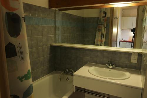 een badkamer met een wastafel, een bad en een spiegel bij Résidence Les Bergers in L'Alpe-d'Huez