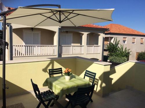 einen Tisch und Stühle auf einem Balkon mit Sonnenschirm in der Unterkunft Apartment M&M in Zadar