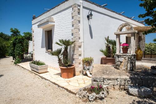 a white house with potted plants in front of it at Agriturismo Grotta Di Figazzano in Cisternino