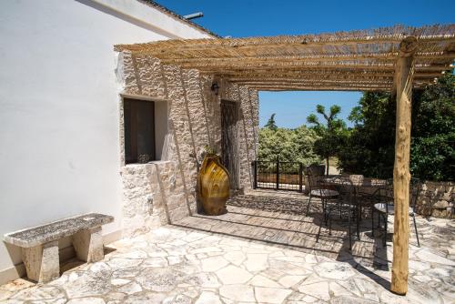 a patio with a wooden pergola and a vase at Agriturismo Grotta Di Figazzano in Cisternino