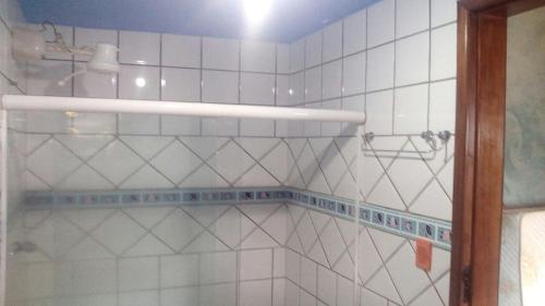 a bathroom with a shower with white tiled walls at Pousada Ponta de Areia do Bixão in Itaúnas