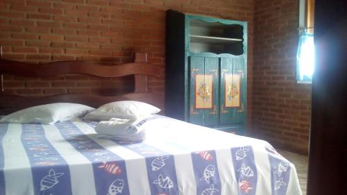 a bedroom with a bed with a blue and white blanket at Pousada Ponta de Areia do Bixão in Itaúnas