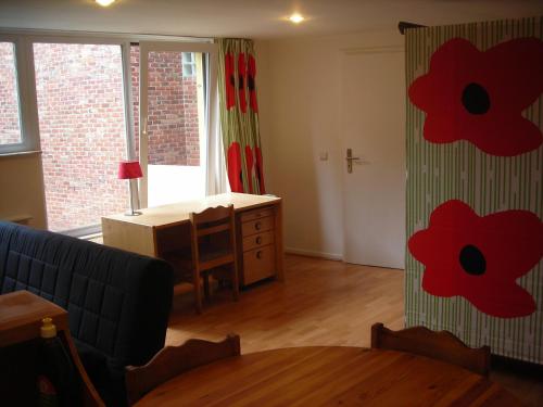 una sala de estar con una mesa y flores rojas en las cortinas en Huize Rafael, en Lovaina