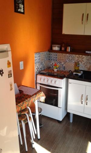 a kitchen with a stove and a table in it at Cabanas do Lorde in Praia do Rosa