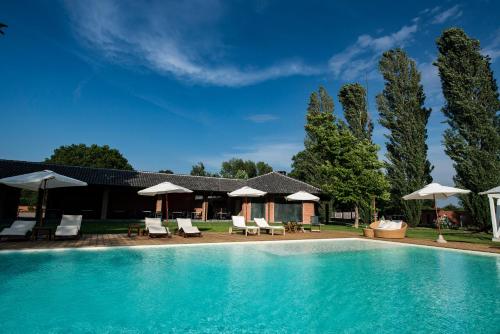 a pool with chairs and umbrellas next to a house at Agriturismo Tenuta "Il Cigno" in Villanterio