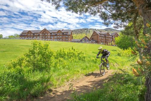 
a man riding a bike on top of a dirt road at Burke Mountain Hotel and Conference Center in East Burke
