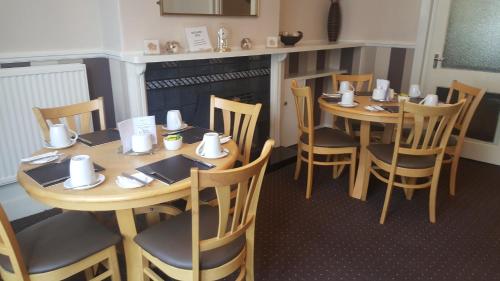 a restaurant with wooden tables and chairs and a fireplace at The Penkelie in Southport