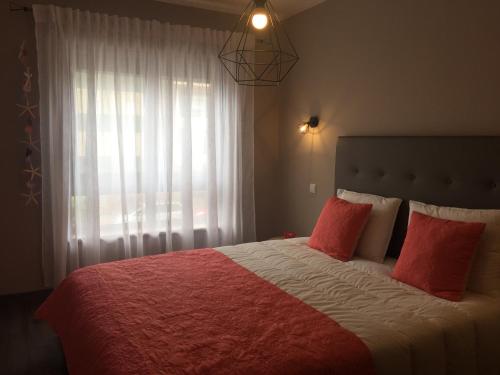 a bedroom with a bed with red pillows and a window at The Lighthouse Apartment in Praia da Barra
