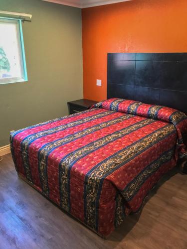a bedroom with a large bed with an orange wall at Highland Park Motel in Los Angeles