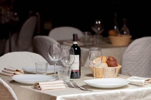 a table with a bottle of wine and glasses on it at Hotel Le Rotonde in Massaciuccoli