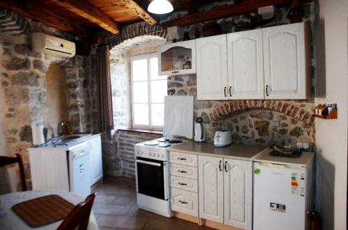 a kitchen with white appliances and a brick wall at Apartments Gudco in Perast