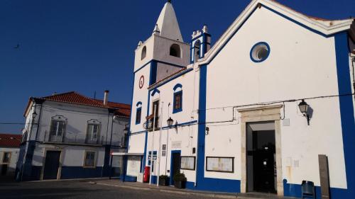 a white building with a clock tower on a street at Route 2 Torrão in Torrão