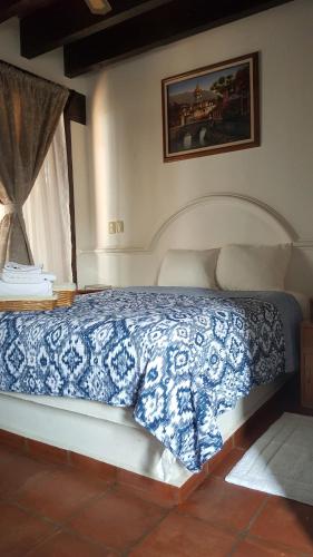 a bedroom with a bed with a blue and white bedspread at La Capilla Hotel Boutique in Valle de Bravo
