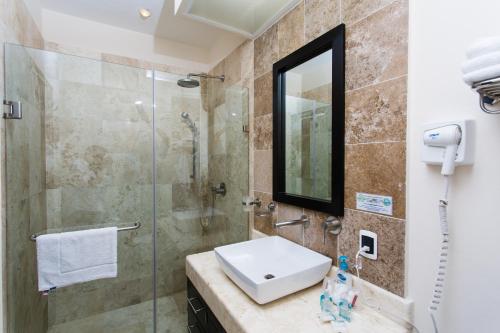 a bathroom with a glass shower and a sink at Oceanfront el Faro Surf 302 in Playa del Carmen