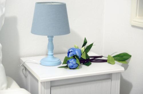 a table with a lamp and blue flowers on it at Porto Smart Apartments- airport in Perafita