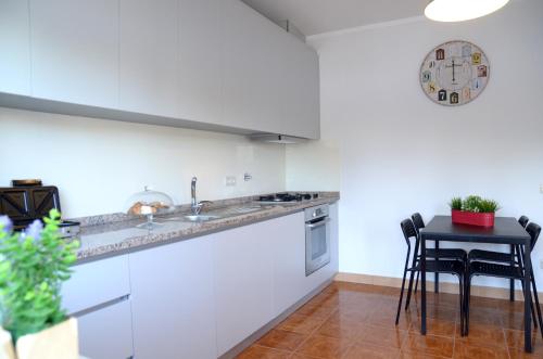a kitchen with white cabinets and a black table at Porto Smart Apartments- airport in Perafita
