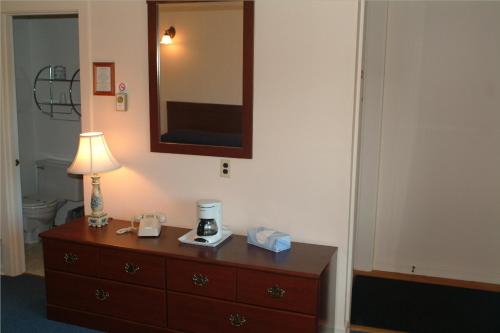 a bedroom with a dresser with a lamp and a mirror at Grand View Motel in Wilmington