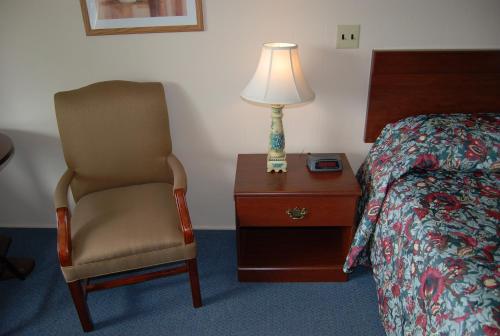 a bedroom with a bed and a chair and a lamp at Grand View Motel in Wilmington