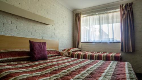 a hotel room with a bed and a window at Arabella Motor Inn (formerly South Tweed Motor Inn) in Tweed Heads