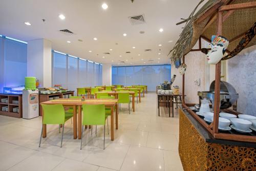 un restaurante con mesas de madera y sillas verdes en Whiz Prime Hotel Balikpapan, en Balikpapan