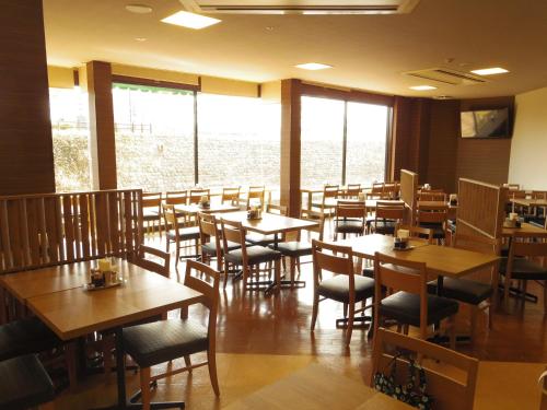 a restaurant with wooden tables and chairs and windows at Hotel Route-Inn Kumamoto Ekimae in Kumamoto