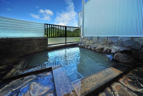 a pool of water next to a building with a fence at Harunako Onsen Yusuge in Takasaki
