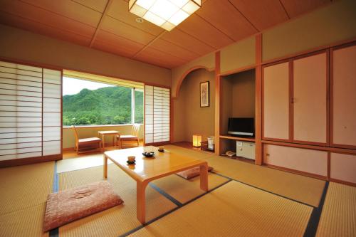 a living room with a table and a large window at Harunako Onsen Yusuge in Takasaki