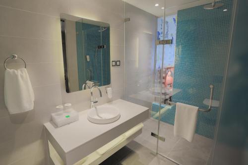 a white bathroom with a sink and a shower at IBIS Styles Ulaanbaatar Polaris in Ulaanbaatar