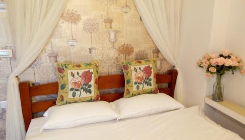 羅東鎮的住宿－維多利亞民宿 ，一张带两个枕头和花瓶的床