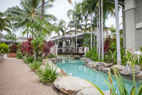a swimming pool in front of a house with palm trees at 160 Temple Swimout Apt in Port Douglas