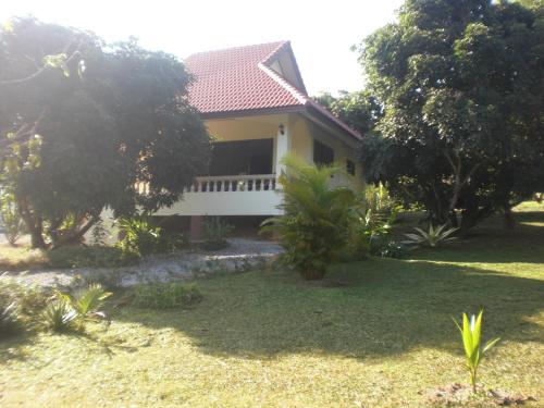 a yellow house with a porch and trees at House of Garden in Chiang Rai