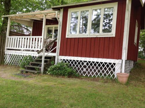 a red house with a porch and a window at Aggarps Stugor in Kulltorp