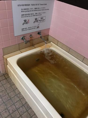 a bath tub in a bathroom with a sign on the wall at Oyado Hana in Nachikatsuura