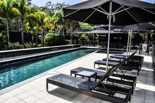 a swimming pool with lounge chairs and an umbrella at The Bay Apartments in Hervey Bay