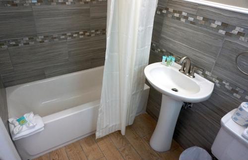 a bathroom with a sink and a toilet and a bath tub at Beachside Resort in Wildwood