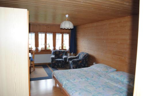 ein Schlafzimmer mit einem Bett und zwei Stühlen darin in der Unterkunft Studio Glaus in Wilderswil