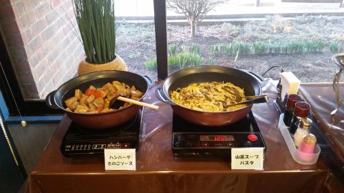 two pots of food sitting on top of a stove at Hotel Hyper Hills Hirosaki in Hirosaki