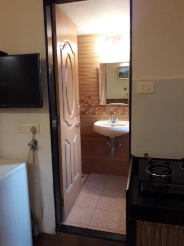 a bathroom with a sink and a toilet and a door at Bis-LIN Home Stay in Panaji