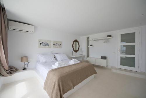 a white bedroom with a bed and a mirror at Diles Villas & Suites Mykonos in Tourlos