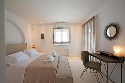 a bedroom with a bed and a desk and a mirror at Diles Villas & Suites Mykonos in Tourlos