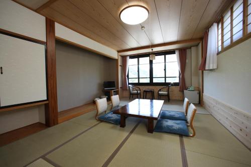 a dining room with a table and chairs and windows at Nezame Hotel in Agematsu