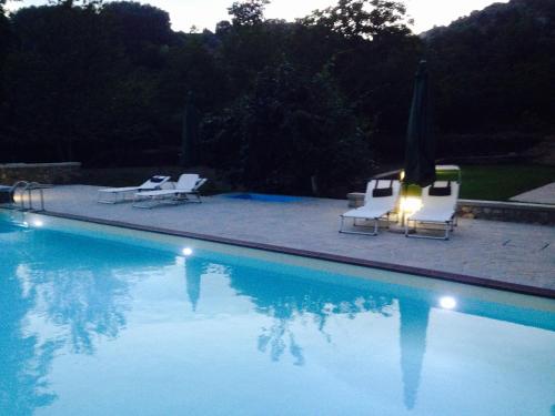 una piscina con 2 sillas y una sombrilla en Monnalisa, en Castiglione di Garfagnana